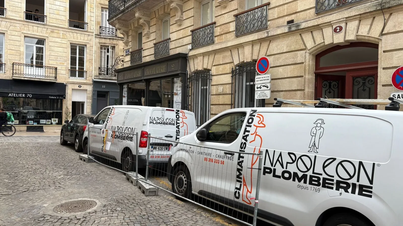 Les véhicules de Napoléon Plomberie stationnés devant l'entreprise, dans une rue de Bordeaux
